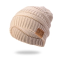 Detail of beige cable knit beanie featuring a brown leather C.C patch and soft ribbed texture - Beige