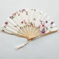 Flat lay of an open folding fan featuring delicate purple floral patterns and white tassel - NO2 White