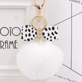 Detailed view of white fluffy pompom keychain with a polka dot bow and gold metal clasp - White