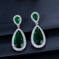 Gros plan de boucles d'oreilles en argent avec zircons vert émeraude sur cuir noir - Vert