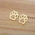 Minimalist gold-plated hollow paw print stud earrings on a natural wood surface - Gold