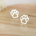 Minimalist silver animal paw print stud earrings with hollow design on wooden surface - Steel