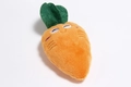 Macro detail of plush carrot dog toy featuring orange fleece and green embroidered leaves - Carrot