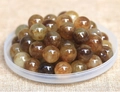 Macro shot of polished natural golden rutilated quartz beads with internal needle inclusions - 8mm / Amber Gold
