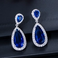 Macro view of teardrop halo earrings with deep blue gemstones and white zircon pave - Blue