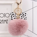 Close-up of pink fluffy pompom keychain with polka dot bow and golden hardware - Dusty Pink
