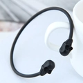 Close-up of a matte black skull cuff bracelet hanging on a white ceramic mug handle - Black