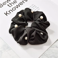 Detail of black satin scrunchie featuring white pearl embellishments and golden trim - Pearl Satin Black