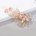 Dettaglio di fiori in tessuto rosa e foglie dorate su un pettine da sposa elegante - Rosa