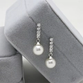 Detail view of silver pearl earrings with zircons on a grey velvet jewelry box display - Pearl Dangle Silver (JED254)