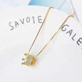 Elegante collar con colgante de corona dorada y circonitas blancas en un plato blanco - Dorado