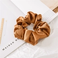 Macro detail of glossy bronze satin silk scrunchie showing delicate fabric folds - Brown