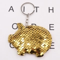 Detailed close-up of a golden sequin pig keychain with metallic ring on a white paper - Gold