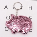 Detail shot of cute pink sequined pig keychain with shiny metallic ring on white background - Pink