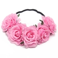 Close-up of five pink faux roses with green leaves on an elastic black headband - Pink