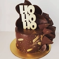 Close-up of golden HO HO HO cake topper on chocolate cake with gold pearl decor - Gold HO HO HO Style