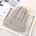 Detailed view of oatmeal cable knit beanie with thick mohair texture on white carpet - One Size / Fleece Lined Beige