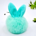 Dettaglio ravvicinato del portachiavi a pompon in peluche verde acqua con orecchie di coniglio - Pompon 8cm + Orecchie di coniglio / Acqua