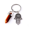Detail view of tiger eye stone pendant and silver Hamsa hand on a metal keychain - Wood Grain