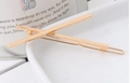 Minimalist gold metal hair clip with a geometric cross bar design on white porcelain - Cross X-Shape / Gold