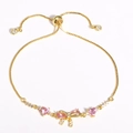 Adjustable gold plated bracelet featuring pink heart gems and a sparkling bow charm - Gold