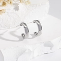 Polished silver C-shape hoop earrings displayed on white stone with dried flowers - Silver