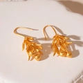 Details von matten goldfarbenen Blattohrringen mit kleinen Perlenanhängern auf Stein - Mattgold Litschiblatt Blume Ohrhaken