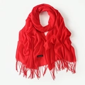 Solid red cashmere feel scarf with tassel edges elegantly folded on white background - Red