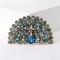 Dettaglio macro di una spilla a pavone vintage con strass blu su metallo dorato antico - Blu Lago