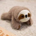 Cute plush sloth fridge magnet in khaki brown on a soft textured rug background - Sloth