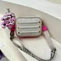 Detail van beige crossbodytas met litchi-textuur en roze rand op stenen trappen - Grijs