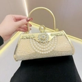 Elegant gold evening clutch bag with sparkling rhinestones and pearls held in hand - Gold