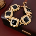 Macro view of vintage gold chain bracelet with black enamel square links on a leather box - Bracelet - Gold