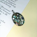 Detailansicht eines ovalen Abalone-Muschel-Mosaikanhängers mit natürlichen Texturen - Oval