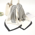 Detail view of a black and white striped silk scarf tied elegantly on a cream handbag - 70-70cm / White Striped (FJ014-2)