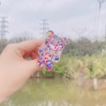 Detailopname van een heldere beervormige telefoonhouder met kleurrijke glitterpailletten - Uitbreidbare Standaard / Multicolor Glitter Beer