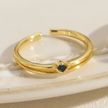Gros plan sur une bague dorée à double rangée ornée d'un zircon bleu en forme de cœur - Pierre Précieuse Bleue en Cœur - Or