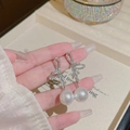 Dettaglio ravvicinato di orecchini a fiocco in argento con strass e perle bianche - Argento