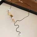 Dettaglio macro della collana con ciondolo a fiore in perla e pietra occhio di tigre - Collana lunga multielemento vintage patchwork di perle e perline di metallo