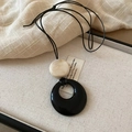 Close-up of black hollow resin pendant and cream bead in a rustic jewelry box - 46# Necklace Black Milk Tea Bead
