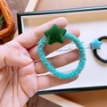 Primo piano di un elastico per capelli in peluche verde con una stella verde scuro soffice - Stella Verde Scuro