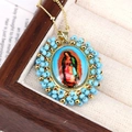 Close-up of Virgin Mary oval pendant with blue beads and golden chain in a jewelry box - Blue