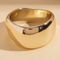Dettaglio di un bracciale rigido dorato ondulato con finitura metallica lucida - Stile con Motivo a Onde Dorate
