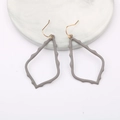 Detail of hollow geometric water drop earrings with grey matte finish on marble stand - Dark Gray