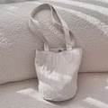 Detail van beige geplooide shopper met fijne textuur en dunne riempjes op zachte achtergrond - Beige