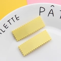 Dettaglio di due fermagli per capelli gialli rettangolari con bordi ondulati su un piatto - 2x5.4cm / Giallo