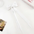 Close-up of a white satin bow hair clip with long ribbons on a decorative background - Double Streamer Bow - Alligator Clip / White