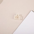 Detail view of square hollow pearl hair claw clip with golden metal spring mechanism - Square