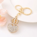Close-up of golden heart and crown keychain with sparkling rhinestones on white tray - Gold Hollow Crown Heart