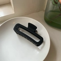 Matte black rectangular shark clip on a white ceramic tray with soft lighting - Black
